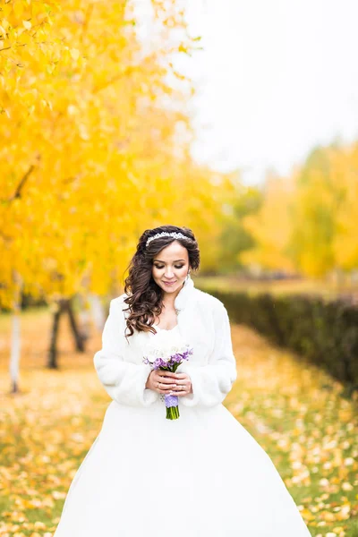 Braut hält Hochzeitsstrauß mit Blumen im Herbstpark — Stockfoto