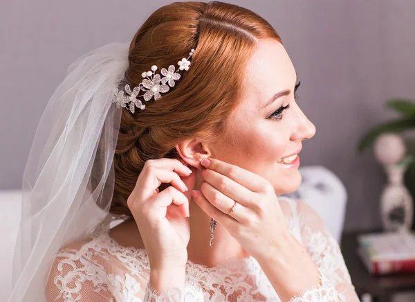 Bruid neemt de oorbellen close-up, bruiloft voorbereiding — Stockfoto