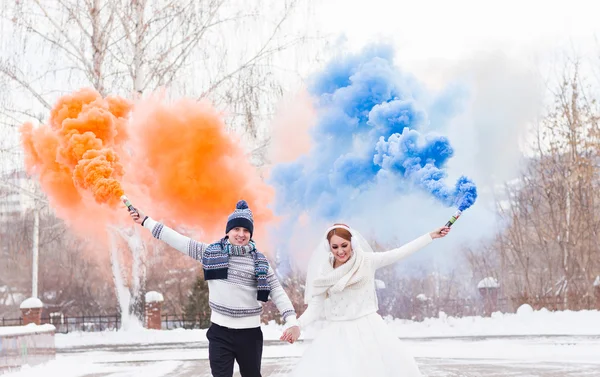 De bruid en bruidegom met rookbommen in de winter — Stockfoto