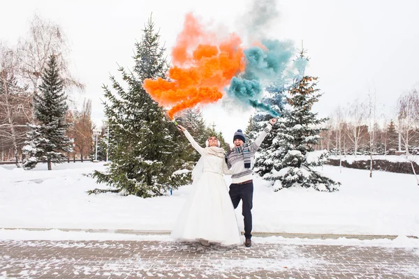 De bruid en bruidegom met rookbommen in de winter — Stockfoto