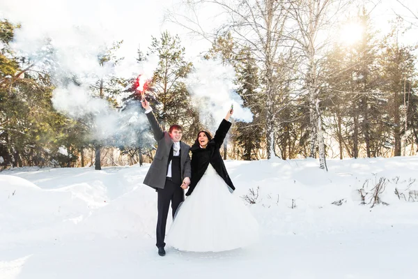 Brautpaar mit Rauchbomben im Winter — Stockfoto