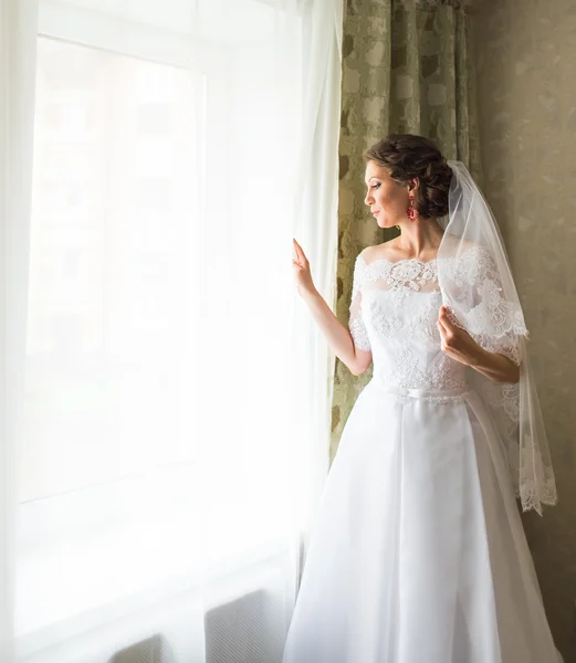 Красивая молодая невеста, стоящая у окна, ожидая — стоковое фото