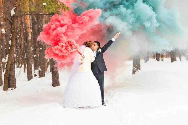 A noiva e o noivo com bombas de fumaça no inverno — Fotografia de Stock