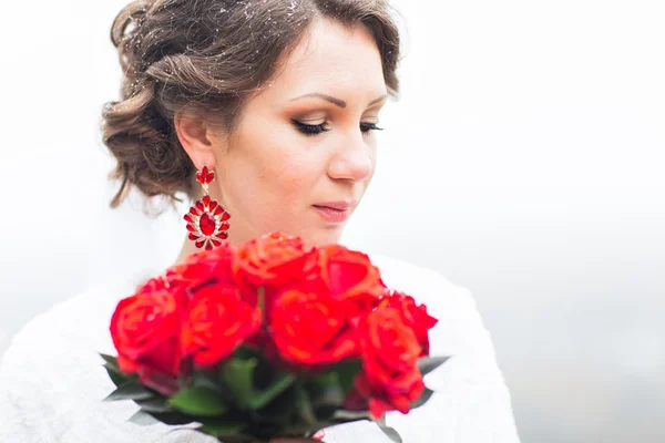 Noiva de inverno segurando buquê de rosas vermelhas — Fotografia de Stock