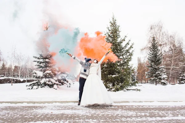 Coppia nuziale con fumo di colore nel parco invernale. Bomba a colori — Foto Stock