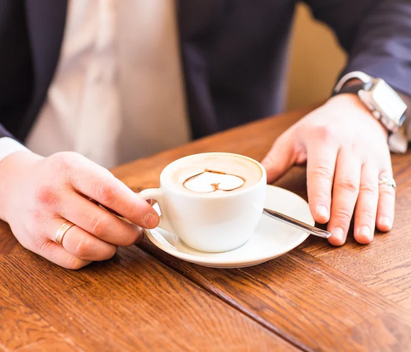 Uomo in possesso di tazza di caffè su sfondo di legno — Foto Stock