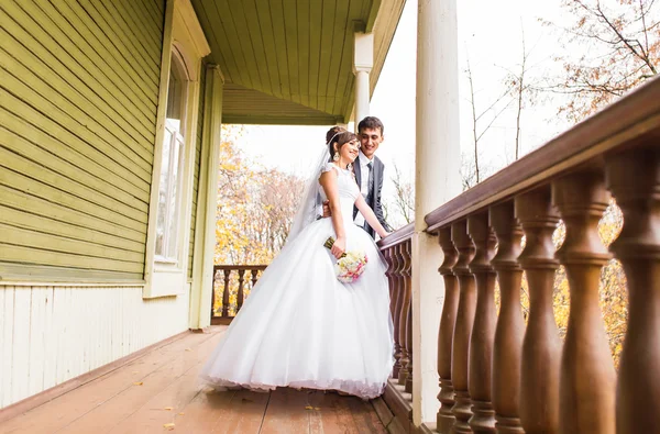Bruid en bruidegom staan in de buurt van een houten huis. Bruiloft in rustieke stijl. — Stockfoto