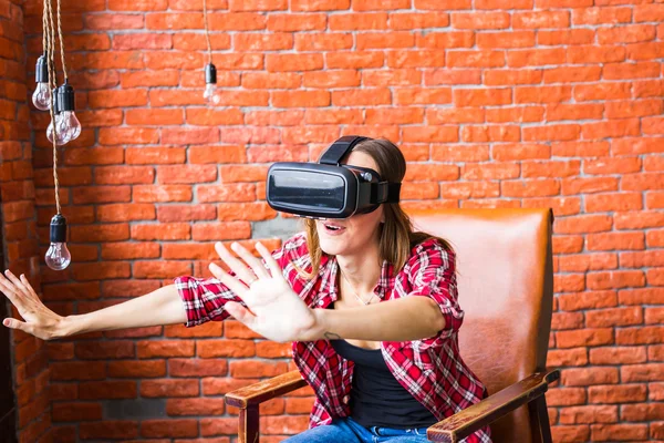 Kadın sanal gerçeklik gözlüğü kullanarak bir şeye dokunuyor.