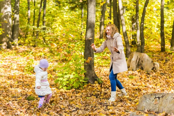 Niña y su madre jugando en el parque de otoño — Foto de Stock