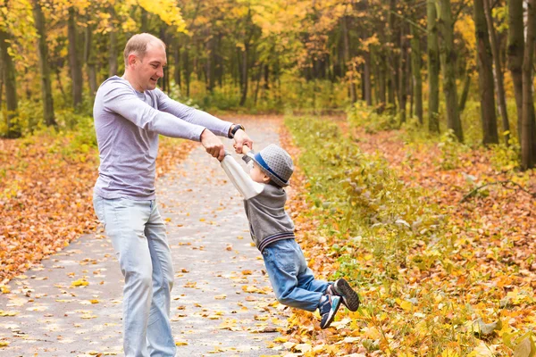 Padre lanza a su feliz hijo riendo en el parque de otoño — Foto de Stock