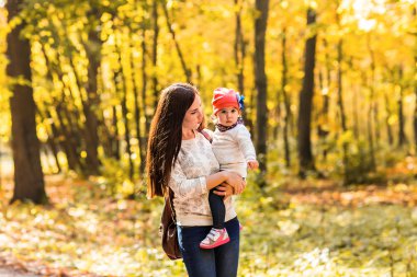 Genç anne ve küçük kızı sonbaharda eğleniyor.