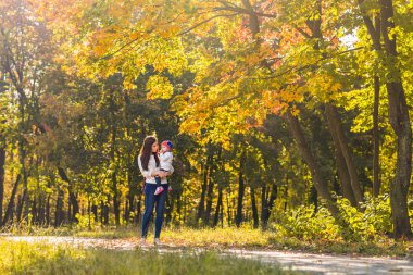 Genç anne ve küçük kızı sonbaharda eğleniyor.