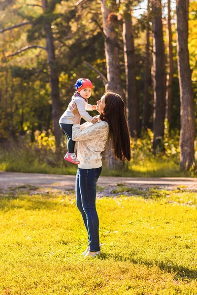 Giovane madre che gioca con sua figlia nel parco autunnale — Foto Stock