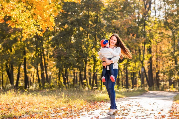 Jonge moeder spelen met haar dochter in de herfst park — Stockfoto