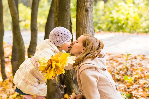 Little girl kissing her mother, autumn outdoor