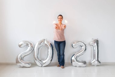 Yeni yıl kutlaması ve parti konsepti - Beyaz arka planda gümüş 2021 balonları yakınında maytaplı mutlu genç kadın.