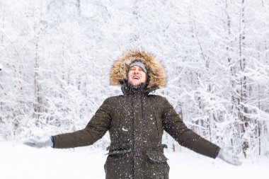 Kış şapkalı yakışıklı, karlı doğada komik bir portre.