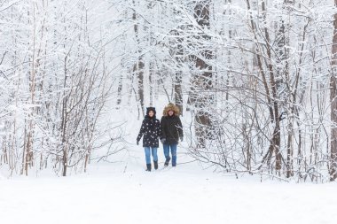 Karlı bir parkta yürüyen genç bir çift. Kış mevsimi.