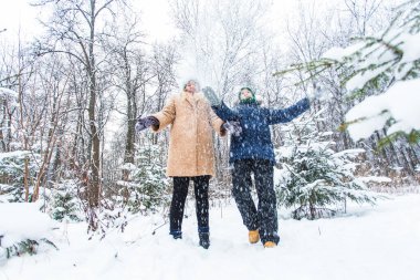 Ebeveynlik, eğlence ve sezon konsepti - Mutlu anne ve oğul kış ormanlarında kar ile oynayıp eğleniyorlar