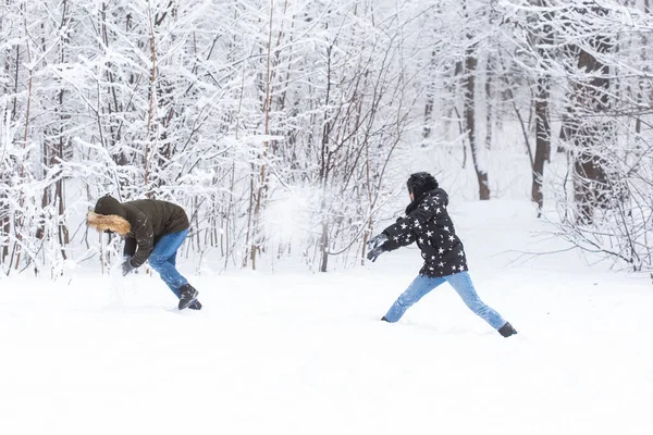 Estilo de vida, temporada e conceito de lazer - Engraçado casal jogando bola de neve no parque de inverno — Fotografia de Stock