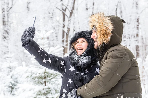 Stagione e concetto di relazione - Coppia divertente scattare selfie nel periodo invernale — Foto Stock