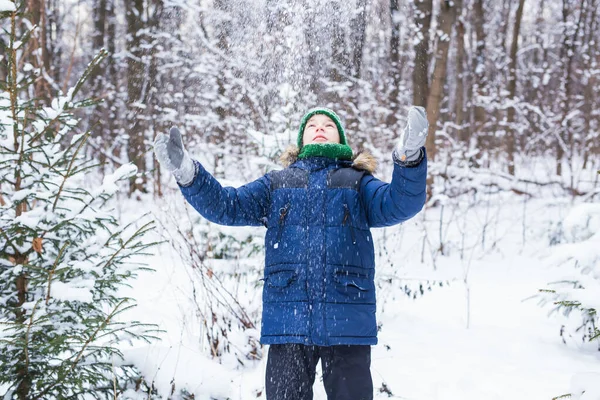 Mignon jeune garçon joue avec la neige, amusez-vous, sourit. Adolescent dans le parc d'hiver. Style de vie actif, activité hivernale, jeux d'hiver en plein air, boules de neige. — Photo