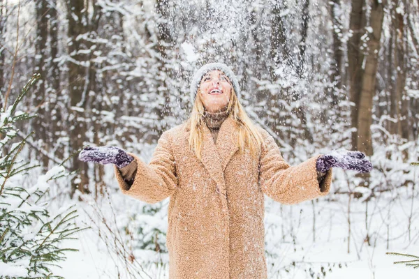 Jeune femme jetant de la neige dans les airs lors d'une journée ensoleillée d'hiver, elle est heureuse et amusante. — Photo