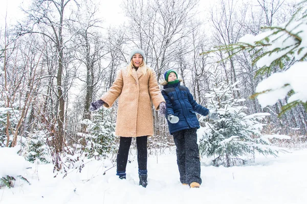 Parenting, fun et concept de saison - Bonne mère et son fils s'amusent et jouent avec la neige dans la forêt d'hiver — Photo