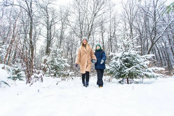 Parenting, fun et concept de saison - Bonne mère et son fils s'amusent et jouent avec la neige dans la forêt d'hiver — Photo