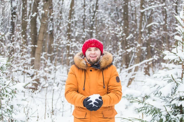 Joven arrojando nieve en el bosque de invierno. Un tipo divirtiéndose al aire libre. Actividades de invierno. — Foto de Stock