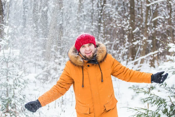 Jeune homme jetant de la neige dans la forêt d'hiver. Le gars s'amuse dehors. Activités hivernales. — Photo