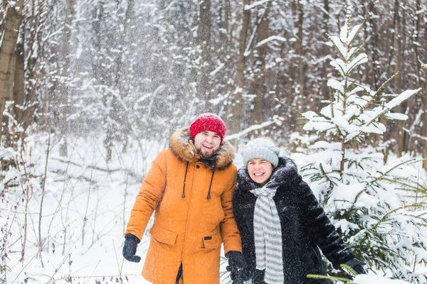 Amour, saison, amitié et concept de personnes - jeune homme et femme heureux s'amuser et jouer avec la neige dans la forêt d'hiver — Photo