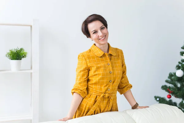 Portret van een lachende jonge vrouw in de buurt van een kerstboom. Wintervakantie concept. — Stockfoto