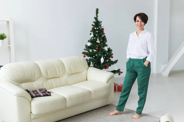 Šťastná žena. Vánoční stromek s dárky pod ním. Dekorovaný obývací pokoj — Stock fotografie