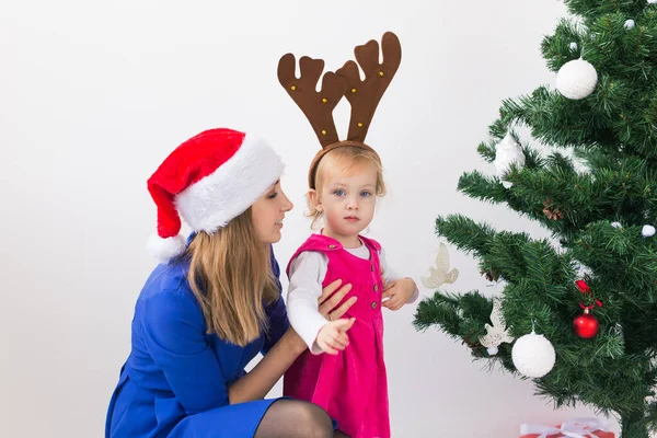 圣诞节的概念- -母亲和她的小女儿在客厅里挂着圣诞树 — 图库照片