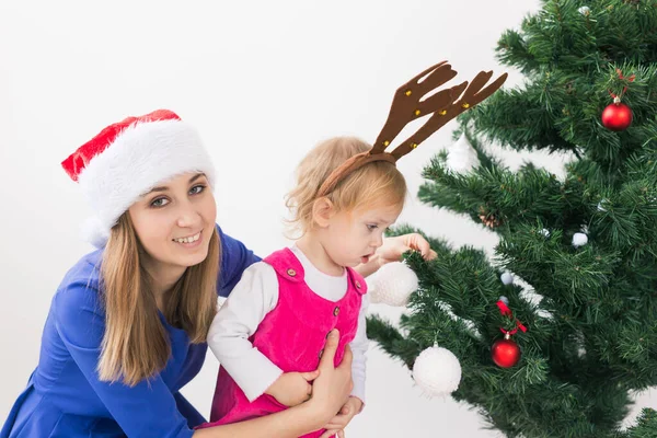 圣诞节的概念- -母亲和她的小女儿在客厅里挂着圣诞树 — 图库照片