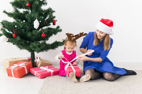 Uśmiechnięta matka otwiera prezenty świąteczne z córeczką w pokoju w tle. Sezon zimowy. Macierzyństwo. Wesołych Świąt. Nowy Rok. — Zdjęcie stockowe