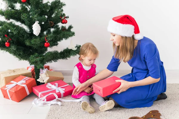 Χαμογελαστή μητέρα ανοίξει τα Χριστούγεννα δώρα με το μωρό κόρη στο δωμάτιο στο παρασκήνιο. Χειμερινή περίοδος. Μητρότητα. Καλά Χριστούγεννα. Νέο έτος. — Φωτογραφία Αρχείου