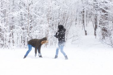 Yaşam tarzı, sezon ve eğlence konsepti - kış parkında kartopu oynayan komik çift