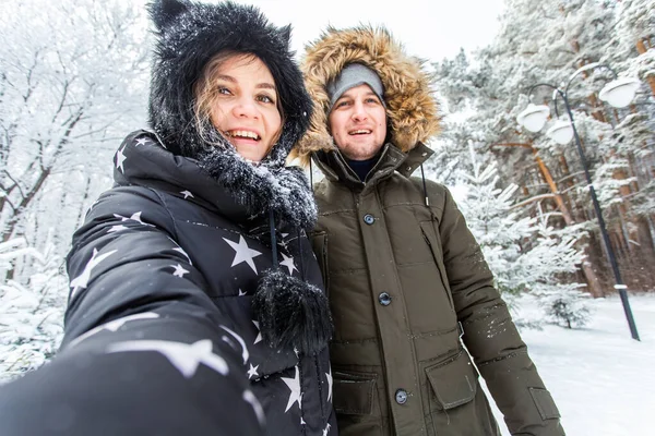 Technologie i koncepcja relacji - Szczęśliwa uśmiechnięta para robi selfie w zimowym lesie na zewnątrz — Zdjęcie stockowe