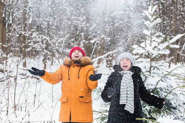 Amour, saison, amitié et concept de personnes - jeune homme et femme heureux s'amuser et jouer avec la neige dans la forêt d'hiver — Photo