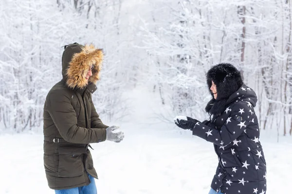 Divertimento, estação e conceito de lazer - casal amor joga madeira de inverno na neve. — Fotografia de Stock