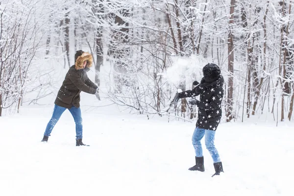 생활 방식, 계절, 여가 개념 - 겨울 공원에서 눈덩이 놀이를 하는 재미있는 부부 — 스톡 사진