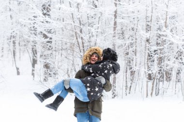 Genç çift karlı bir parkta eğleniyor. Kış mevsimi.
