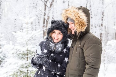 Sezon, aşk, teknoloji ve eğlence konsepti. Mutlu çift kış arkaplanı boyunca akıllı telefonla selfie çekiyor.