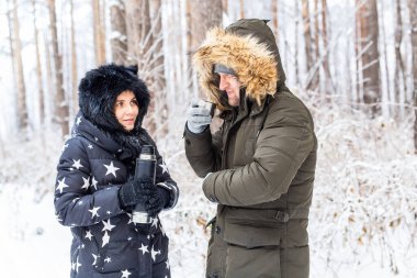 Birbirine aşık genç bir çift termostan sıcak bir içecek içer ve kış doğasının tadını çıkarır..