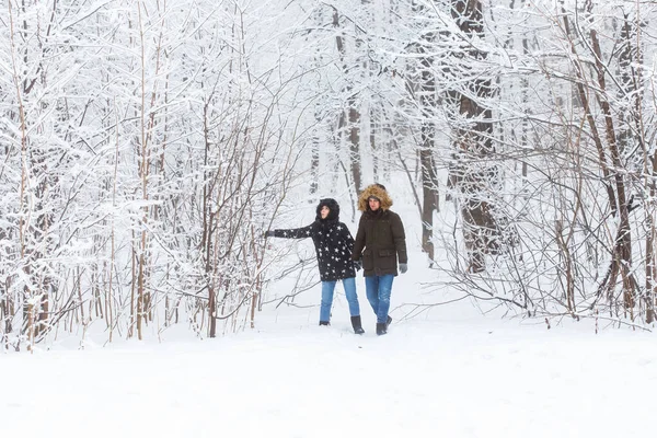 Casal jovem caminhando em um parque nevado. Temporada de Inverno. — Fotografia de Stock