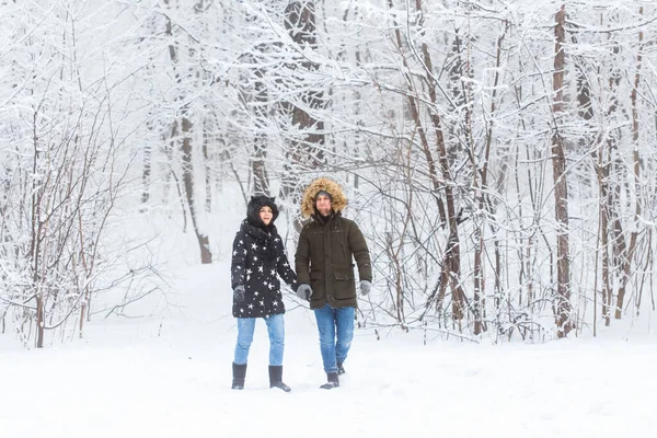 Młoda zakochana para spaceruje po zaśnieżonym lesie. Aktywne ferie zimowe. — Zdjęcie stockowe