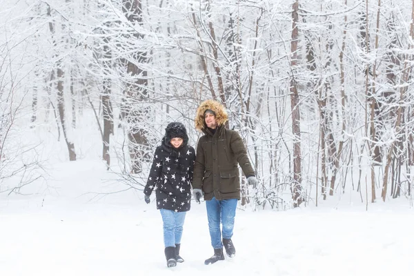 눈덮인 공원을 걷고 있는 젊은 부부. 겨울 계절. — 스톡 사진