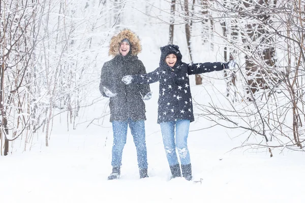 L'amour, la relation, la saison et le concept d'amitié - l'homme et la femme s'amusent et jouent avec la neige dans la forêt hivernale — Photo